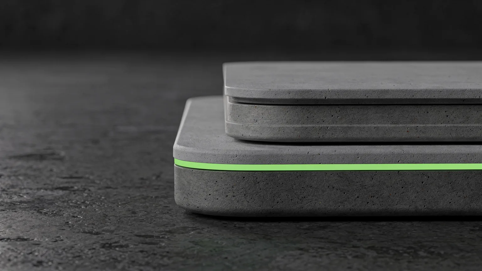 Two stacked grey rubber floor slabs of different thicknesses with a thin volt-green edge strip on a dark concrete floor
